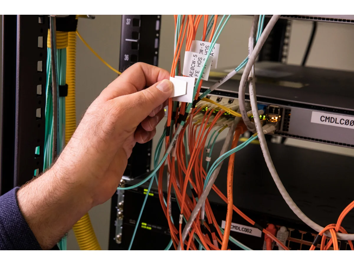 Técnico colocando etiqueta de identificación sobre cables de datos en armario rack
